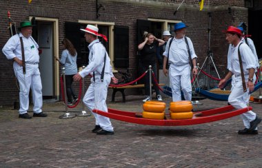 Alkmaar, Hollanda, Mayıs 2022. Peynir taşıyıcıları, renkli hasır şapkalarıyla Alkmaar peynir pazarında. Yüksek kalite fotoğraf