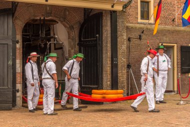 Alkmaar, Hollanda, Mayıs 2022. Peynir taşıyıcıları, renkli hasır şapkalarıyla Alkmaar peynir pazarında. Yüksek kalite fotoğraf