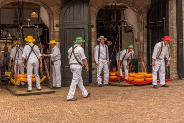 Alkmaar, Hollanda, Mayıs 2022. Peynir taşıyıcıları, renkli hasır şapkalarıyla Alkmaar peynir pazarında. Yüksek kalite fotoğraf