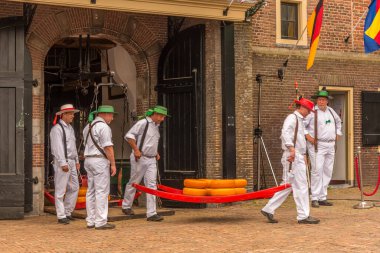 Alkmaar, Hollanda, Mayıs 2022. Peynir taşıyıcıları, renkli hasır şapkalarıyla Alkmaar peynir pazarında. Yüksek kalite fotoğraf