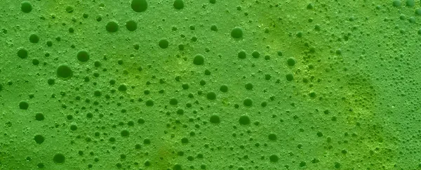 Green bubble banner, soap foam with green liquid. Close up of texture. Flat lay top view