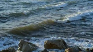 Deniz dalgaları bir marinanın rıhtımında büyük taşlara çarpıyor. San Vincenzo, Toskana, İtalya