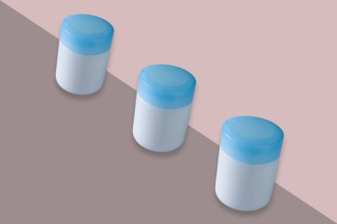 Mavi kapaklı kozmetik kavanozları çift renkli arka planda izole edildi