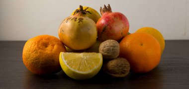 Kışlık meyveler koyu ahşap masada. Ceviz, portakal, mandalina, nar, limon ve ceviz.