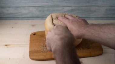 Kesme tahtasındaki bıçakla susamlı ekmek kesmek. Sıcak ev yapımı buharlı yumuşak ekmek.