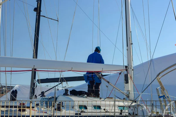 İşçi marinadaki bir teknenin yelkenlisini tamir eder.