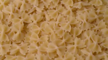 Close up of raw Italian farfalle pasta, rotating. Uncooked traditional food. Mediterranean cuisine