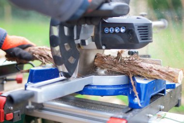 Müteahhit, odun dallarını kesmek için büyük dairesel testere kullanıyor.