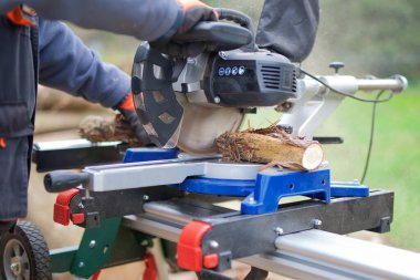 Müteahhit, odun dallarını kesmek için büyük dairesel testere kullanıyor.