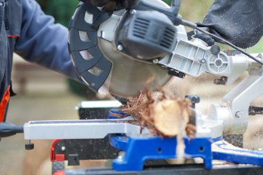 Müteahhit, odun dallarını kesmek için büyük dairesel testere kullanıyor.