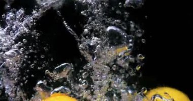 Siyah arka planda suya düşen limonlar