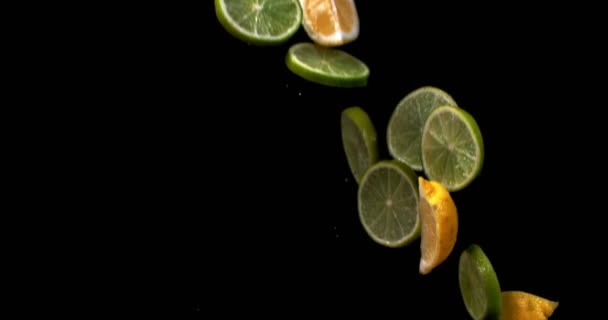 Limão e limão fatiado em cunhas voar para cima e cair em um fundo preto — Vídeo de Stock
