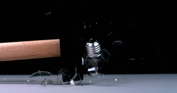 Un martillo rompe una bombilla, sus fragmentos vuelan alrededor — Vídeo de stock