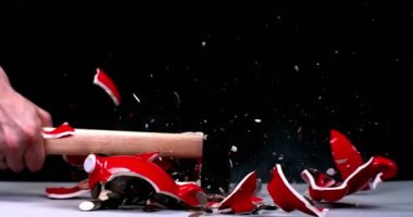 Bir çekiç kumbaranın parçalarını kırıyor ve bozuk paralar farklı yönlere uçuyor.