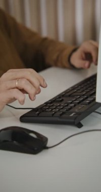Bilgisayarın başında otururken klavyede yazan adam, yakın çekim.