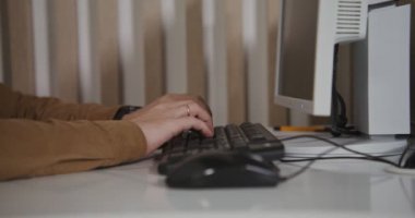 Bilgisayarın başında otururken klavyede yazan adam, yakın çekim.