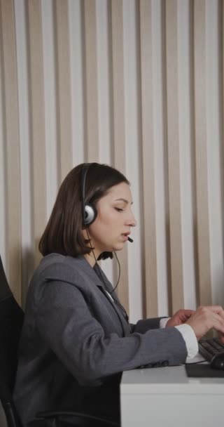 Call center lavoratore una giovane donna in cuffia comunica con un cliente — Video Stock