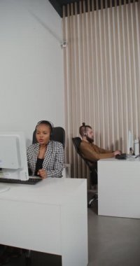 Kulaklık takmış çağrı merkezi çalışanları müşterilerle iletişim kuruyor.