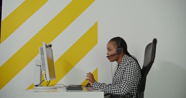 Travailleur du centre d'appels femme afro-américaine dans les écouteurs communique avec le client — Video