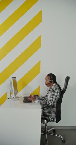 Trabajadora de centro de llamadas afroamericana mujer en auriculares se comunica con el cliente — Vídeo de stock