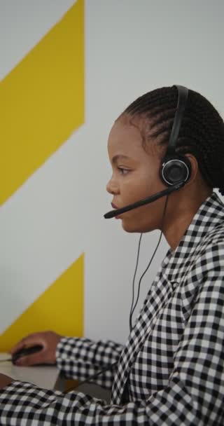 Trabajadora de centro de llamadas afroamericana mujer en auriculares se comunica con el cliente — Vídeos de Stock