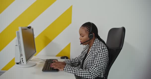 Trabajadora de centro de llamadas afroamericana mujer en auriculares se comunica con el cliente — Vídeo de stock