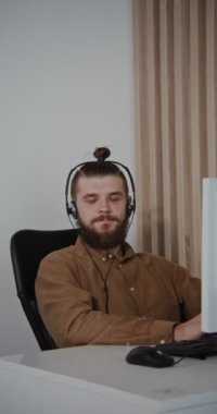 Çağrı merkezi çalışanı. Kulaklıklı genç bir adam kameraya gülümsüyor.