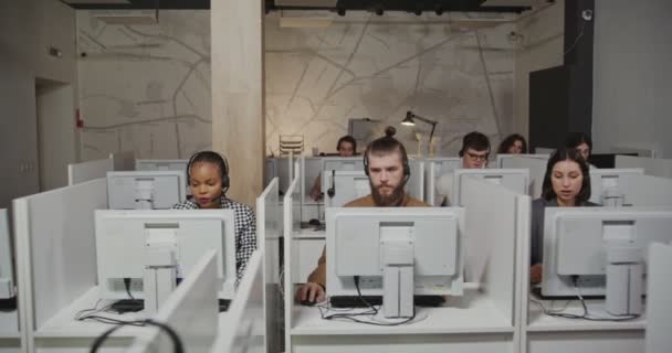 Call center com trabalhadores em microfones com fones de ouvido conversando com clientes — Vídeo de Stock