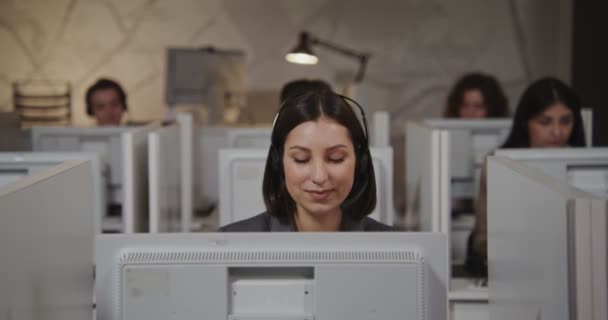 Callcenter-Mitarbeiterin - junge Frau mit Kopfhörer kommuniziert mit dem Kunden — Stockvideo