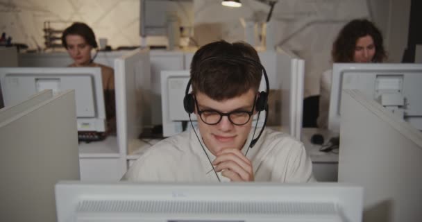 Τηλεφωνικό κέντρο εργαζόμενος - ένας νεαρός άνδρας με ακουστικά επικοινωνεί με έναν πελάτη — Αρχείο Βίντεο