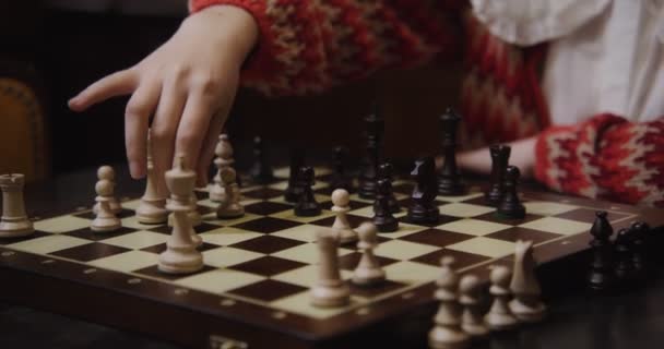 Een jonge vrouw speelt een schaakspel alleen, zittend aan een lange tafel in de bibliotheek — Stockvideo