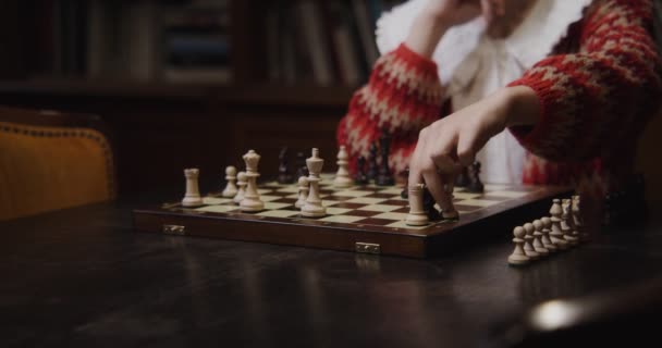 Een vrouw speelt een schaakspel alleen en draait het bord om, verandert van kleur — Stockvideo