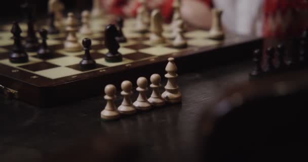 Genç bir kadın tek başına satranç oynuyor, masada oturuyor. — Stok video