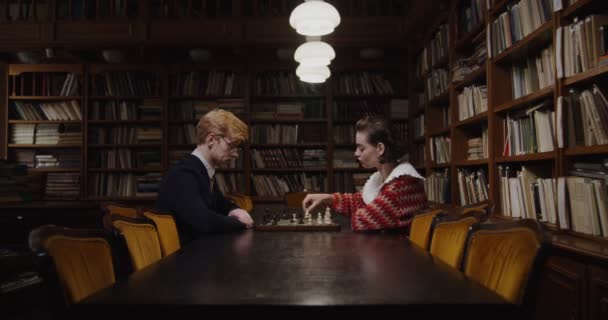 Een man en een vrouw die een schaakspel spelen, tegenover elkaar zitten — Stockvideo