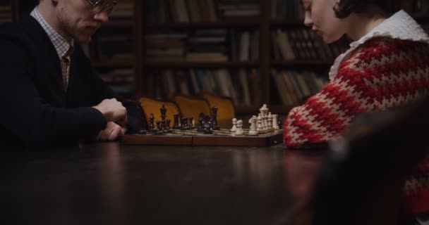 Un hombre y una mujer jugando un juego de ajedrez, sentados uno frente al otro — Vídeo de stock