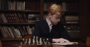 Bir adam tek başına satranç oynamak için konsantrasyonuyla ders çalışıyor.