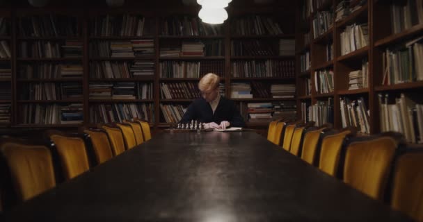 Muž studuje s koncentrací hrát šachy sám, pomocí učebnice — Stock video