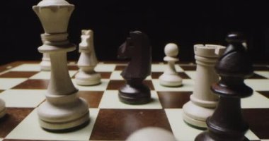 Siyah ve beyaz satranç taşları kaotik bir şekilde satranç tahtasının üzerinde duruyor.