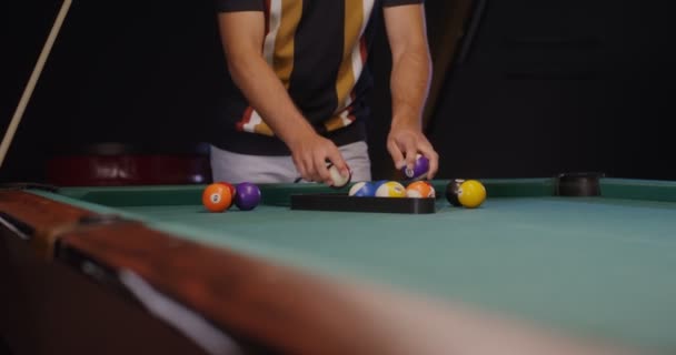 Un jeune homme va jouer au billard, pliant des boules dans un triangle — Video