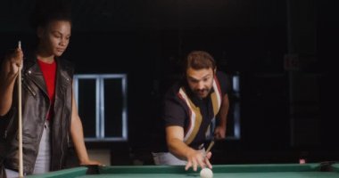 Bir erkek kadına ıstakayı nasıl tutacağını ve bilardoda bir üçgeni nasıl kıracağını gösterir.