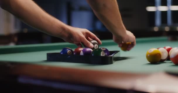 Un jeune homme va jouer au billard, pliant des boules dans un triangle — Video