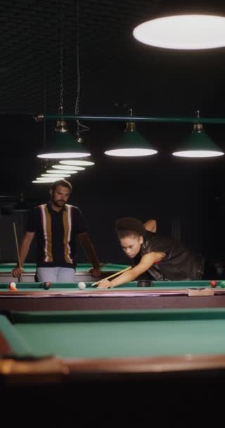 African-American woman is aiming and hitting ball with a cue, playing billiards — Stock Video