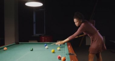 Güzel Afrikalı Amerikalı kadın bilardo kulübünde tek başına bilardo oynuyor.