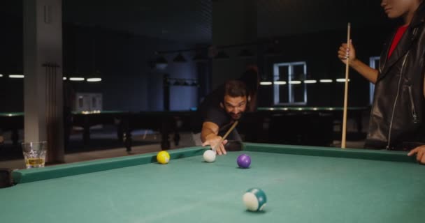 Un jeune homme et une jeune femme jouent au billard, parlent et boivent de la bière. — Video