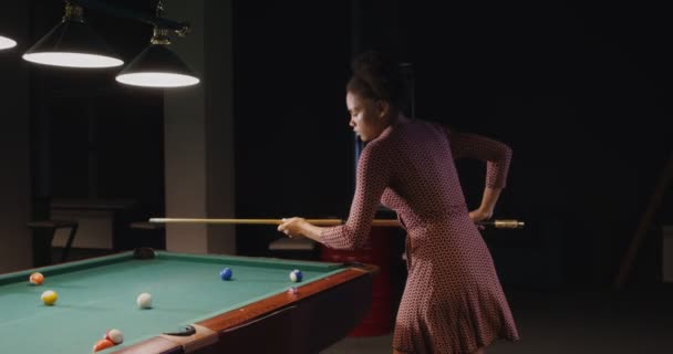 Beautiful young african american woman plays billiards alonein a billiard club — Stock Video