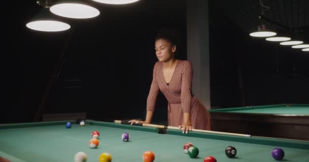 Femme afro-américaine avec la queue dans les mains, se tient appuyé sur une table de billard — Video