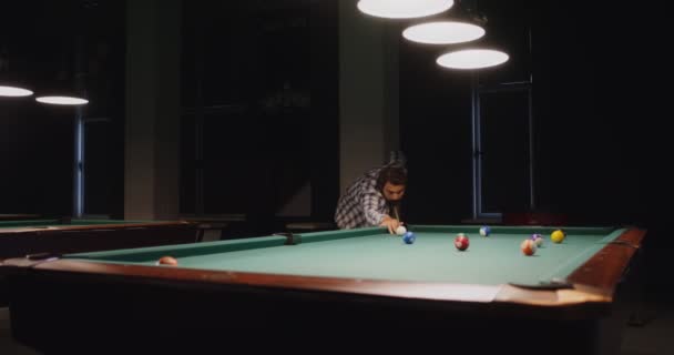 Ένας άντρας παίζει μπιλιάρδο μόνος κάτω από αμυδρά φώτα σε ένα κλαμπ μπιλιάρδου. — Αρχείο Βίντεο