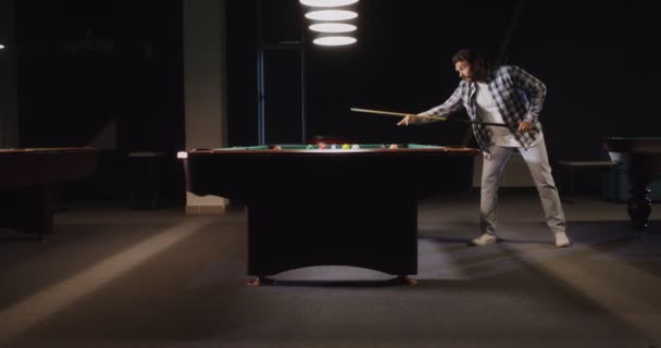 Un uomo gioca a biliardo da solo sotto luci fioche in un club di biliardo — Video Stock