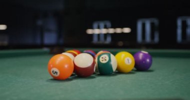 Beyaz bilardo topu kenarlara doğru uçan renkli toplardan oluşan bir üçgen kırıyor.