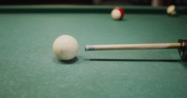 İşaret bilardo masasında duran beyaz topa nişan alıyor, yakın plan.